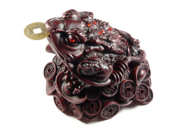 Figurka chińskiej żaby na monetach, trzymająca monetę w pysku.
