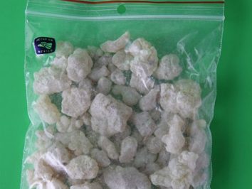 Przezroczysta torebka strunowa z białymi grudkami na zielonym tle.