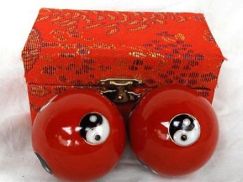 Dwie czerwone kule chińskie z symbolem yin-yang przed ozdobnym czerwonym pudełkiem.