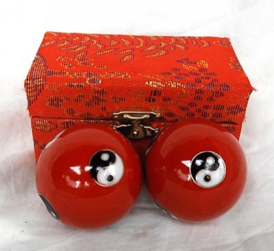 Dwie czerwone kule chińskie z symbolem yin-yang przed ozdobnym czerwonym pudełkiem.