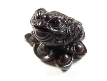 Czarna figurka żaby siedzącej na monetach, symbolizująca bogactwo i szczęście.