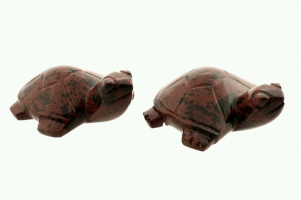 Dwa małe kamienne żółwie ustawione obok siebie na jasnym tle.