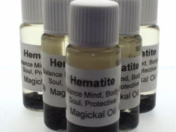 Pięć buteleczek olejku magii z hematytem, ustawionych obok siebie.