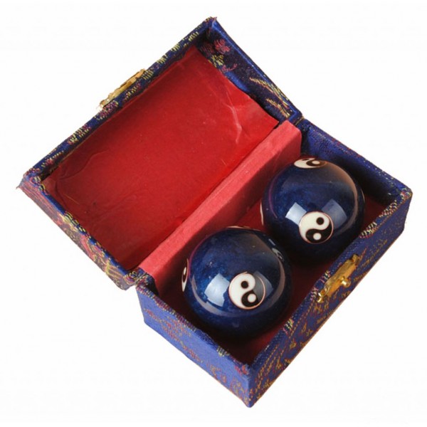 Dwie chińskie kule zdrowia z symbolami yin-yang w ozdobnym pudełku z czerwonym wnętrzem.