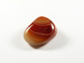 Brązowy, polerowany kamień agat leży na białym tle.