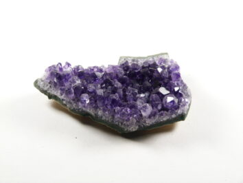 Ametyst kamień ochronny, naturalna szczotka z fioletowymi kryształami na jasnym tle.