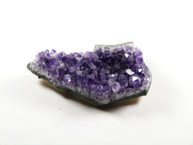 Ametyst kamień ochronny, naturalna szczotka z fioletowymi kryształami na jasnym tle.