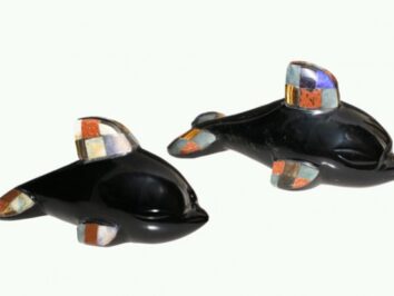 Dwa czarne figurki delfinów z kolorowymi wstawkami na płetwach, ustawione obok siebie.