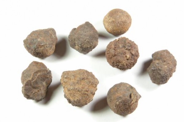 Hematyt - kamień naturalny, surowy, nieszlifowany. Osiem kamieni o nieregularnym kształcie leży na białym tle.