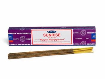 Fioletowe opakowanie i patyczki kadzidełek Satya Sunrise leżące obok siebie na białym tle.