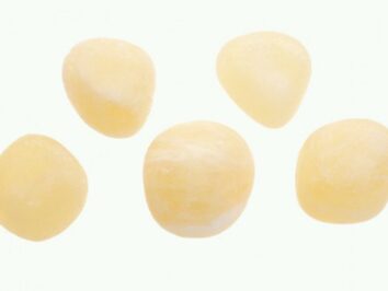Kalcyt złoty/ kalcyt złocisty - kamień gładzony, polerowany, szlifowany i bębnowany w formie otoczaka. Pięć kamieni gładkich kalcytu złotego na białym tle.