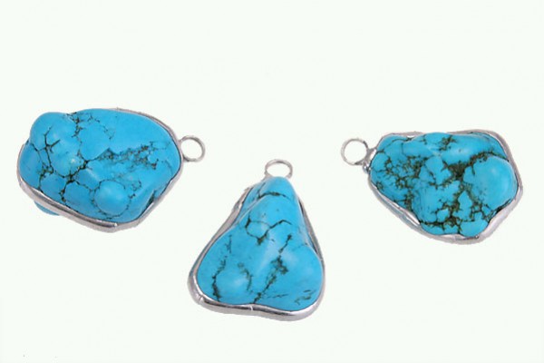 Trzy niebieskie zawieszki z turkusu w metalowych oprawkach na białym tle.