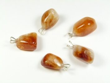 Pięć brązowo-białych kamieni z zawieszkami do biżuterii na białym tle.