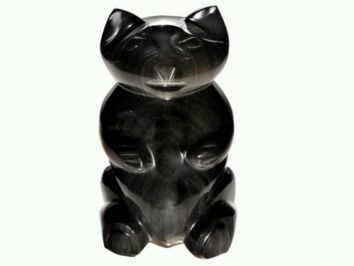 Czarna figurka kota wykonana z kamienia, stojąca na białym tle.