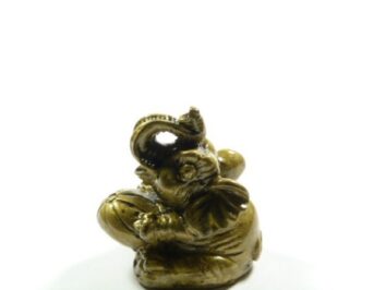 Mała figurka siedzącego słonia z podniesioną trąbą na białym tle.