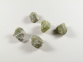 Peridot - kamień naturalny, surowy, nieszlifowany. Pięć surowych, zielonych kamieni leży na białym tle.