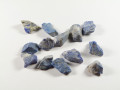 Lapis lazuli - kamień naturalny, surowy, nieszlifowany. Na białym tle leży kilka nieoszlifowanych, niebieskich kamieni lapis lazuli.