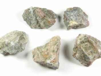 Riolit - kamień naturalny, surowy, nieszlifowany. Pięć surowych brył minerału leży na białym tle.