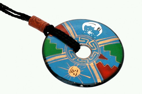 Okrągły wisiorek z kolorowym, etnicznym wzorem, zawieszony na czarnym sznurku.