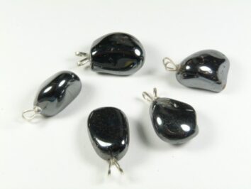Pięć czarnych, połyskujących kamieni hematytu z metalowymi zaczepami do zawieszania.