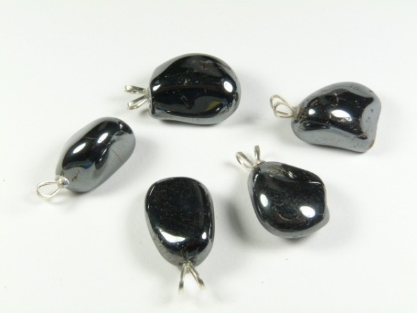 Pięć czarnych, połyskujących kamieni hematytu z metalowymi zaczepami do zawieszania.