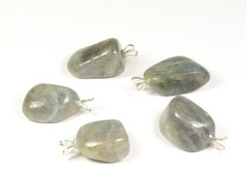 Pięć szlifowanych kamieni z zawieszkami na białym tle, przeznaczonych na wisiorki.