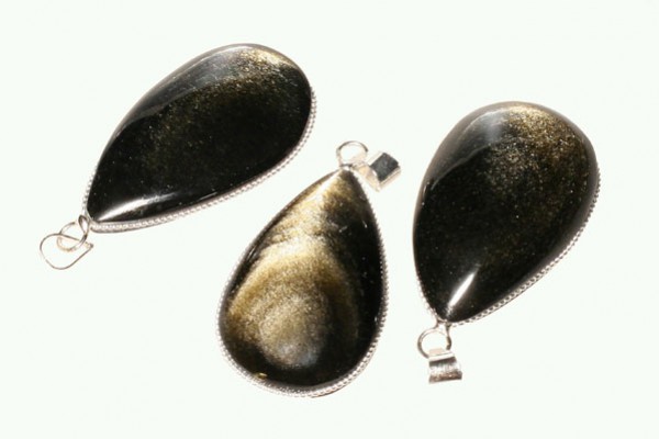 Trzy czarne, błyszczące wisiorki w kształcie kropli z metalową oprawą.