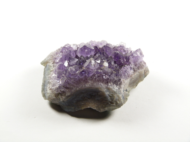 Ametyst szczotka jako naturalny fragment geody z fioletowymi kryształami. Fioletowy kryształ ametystu na białym tle.