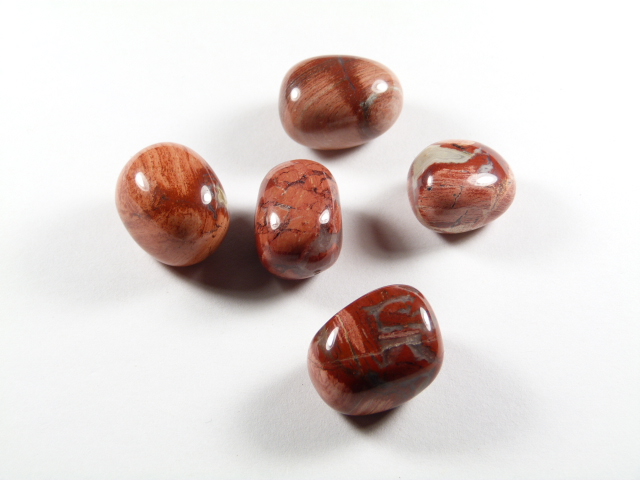 Kamień jaspis makowy poppy gładzony. Pięć wypolerowanych, brązowo-czerwonych kamieni leży na białym tle.