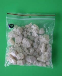 Kopal z Meksyku – naturalna żywica w woreczku strunowym na zielonym tle, Przezroczysta torebka strunowa z kawałkami białych kryształków na zielonym tle.